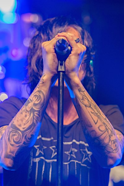 Rocker vor Mikrofon mit Blues Harp Mundharmonika