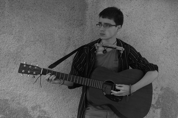 Junge spielt Gitarre hat Mundharmonika mit Halter um Hals
