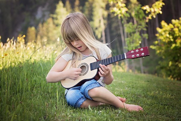 Mädchen spielt Ukulele auf Wiese